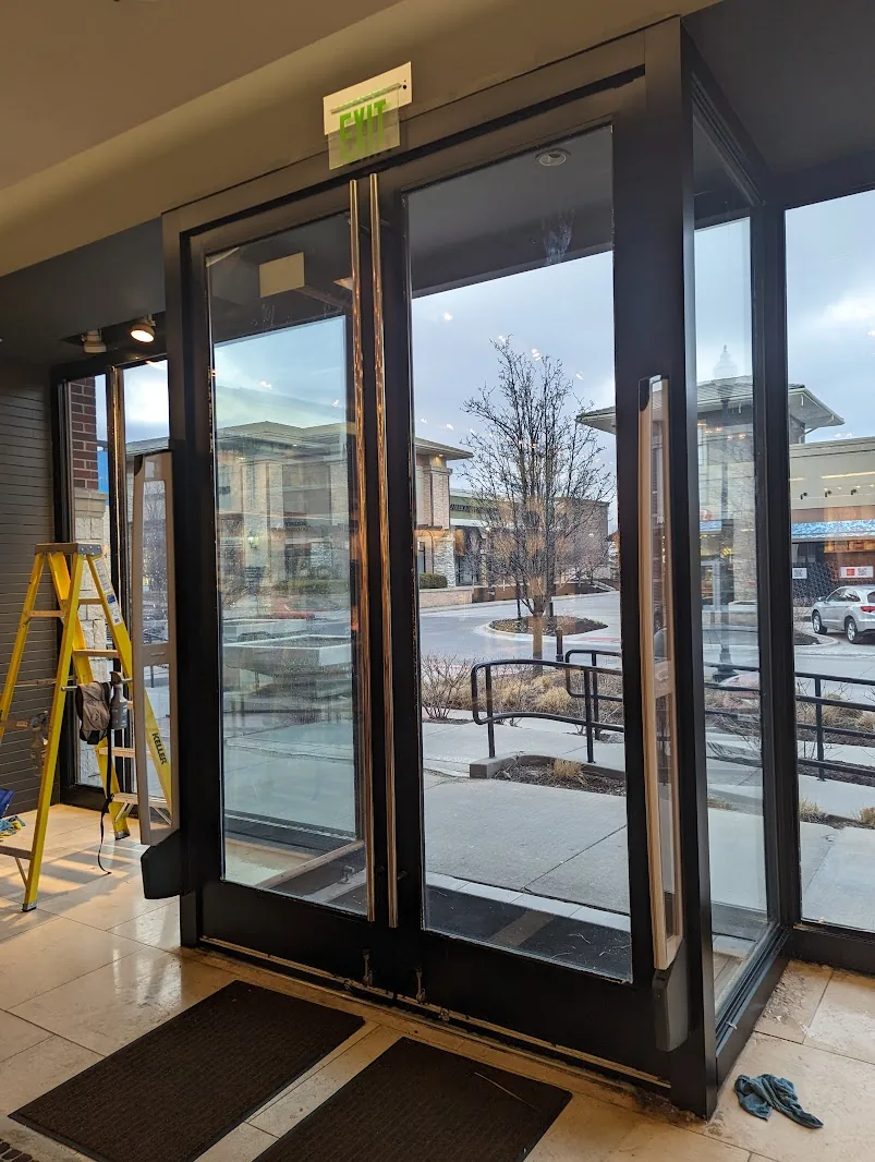 Installer on a ladder applying security film to glass entry doors