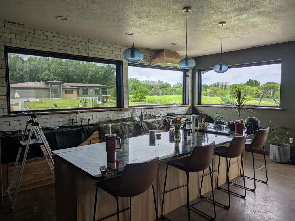 Event room with a long kitchen island and black-framed windows treated with window film