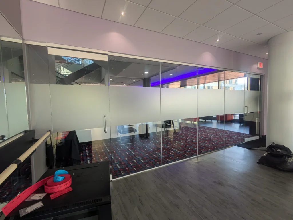 Glass conference room wall with a frosted privacy film band at seated eye level