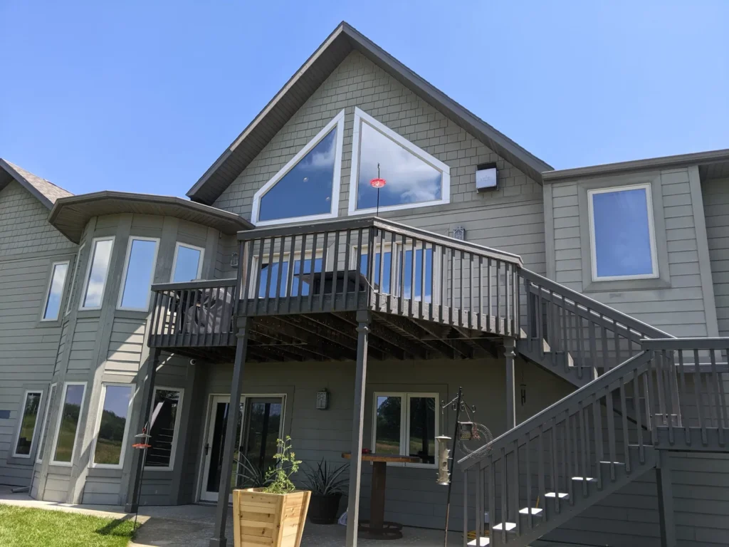Exterior of a two-story home with gable, turret and deck windows treated with window film