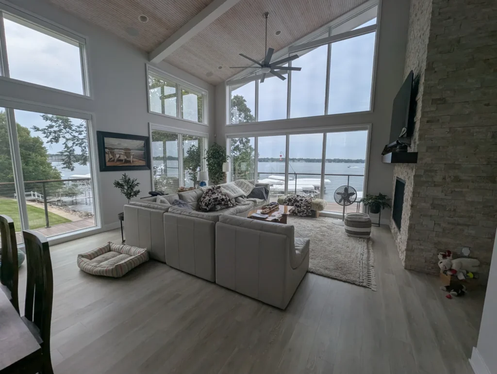 Vaulted great room with tall lake-view windows finished with clear window film