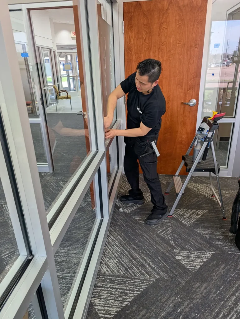 Installer applying safety film along the frame of an interior glass door and sidelight